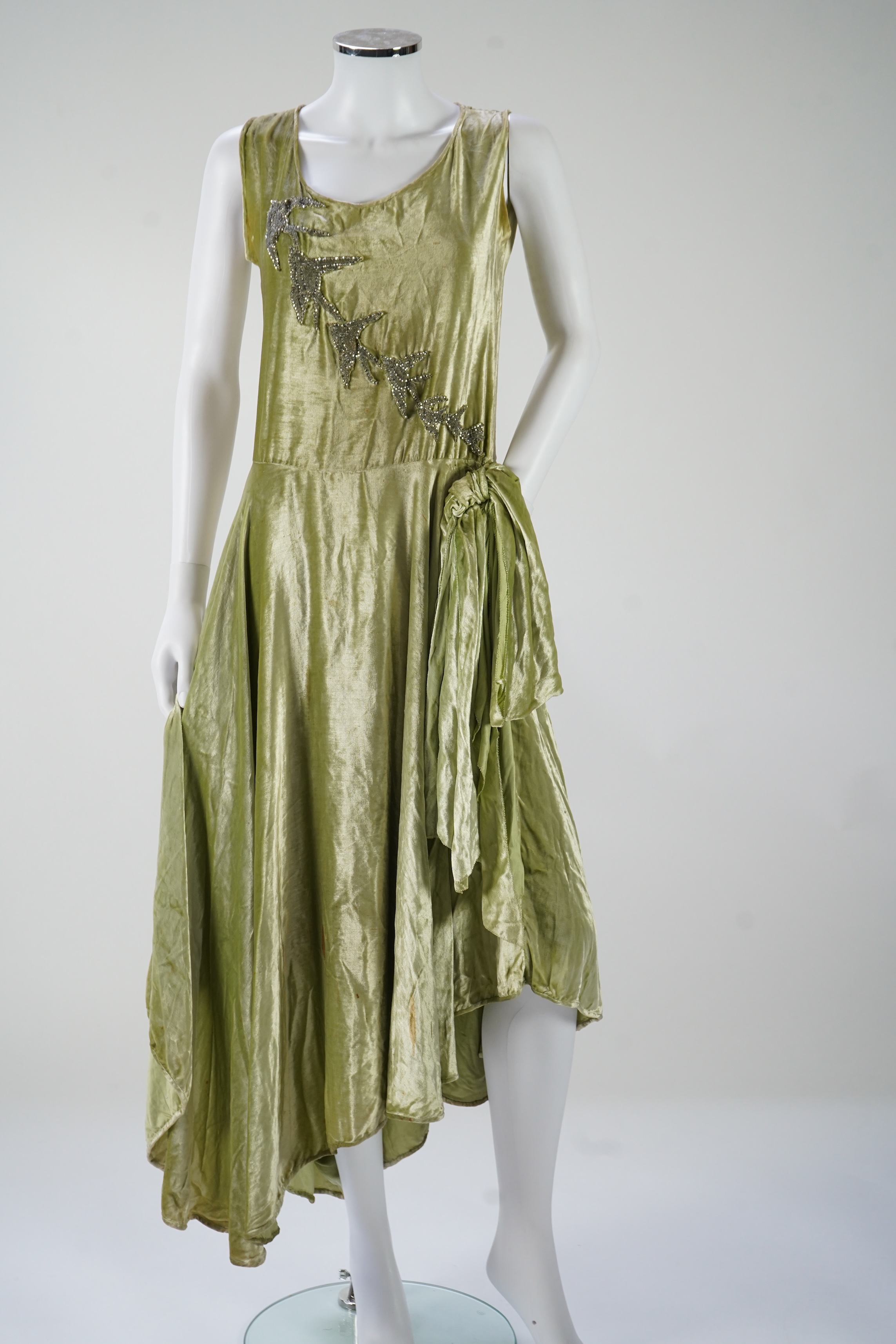 A late 1920’s early 30’s green panne silk velvet evening dress, bias cut, with large diamanté ornamentation and bow on the hip, bust 36 inches, length 55inches. Condition - there is a small hole on the front near arm hol